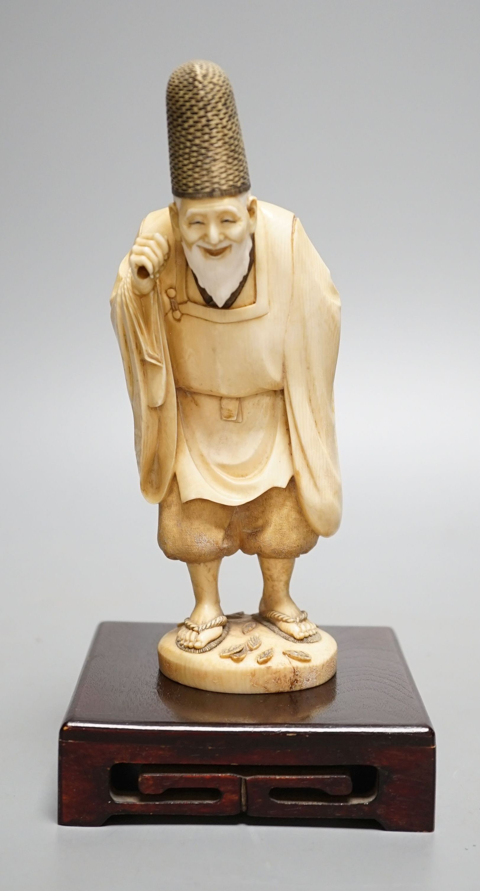 A Japanese ivory figure of a court official, wearing a tall eboshi hat, Taisho period, signed to a lacquer tablet - 18.5cm tall